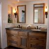 the vanity boasts copper clad mirrors, a matte finished stone slab counter, and a hidden pullout in the center where the towels hang behind a copper wire mesh, also visible in the lower drawers.